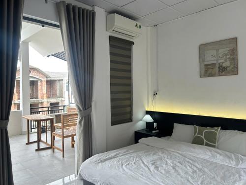 a bedroom with a bed and a balcony with a table at Cốm Homestay in Hue