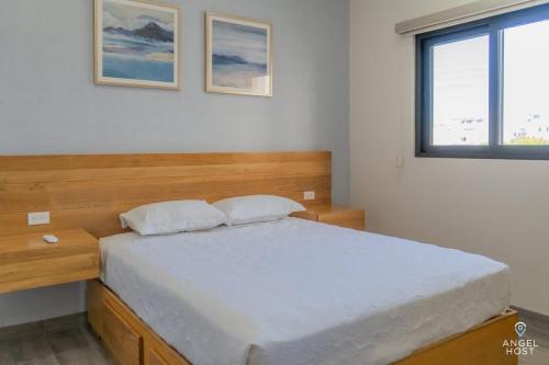 a bedroom with a bed with a wooden headboard and a window at Pool BBQ & a Short Walk to the Malecon in La Paz