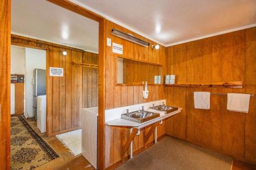 a bathroom with two sinks and wooden walls at Kaha Lodge in Rangataua