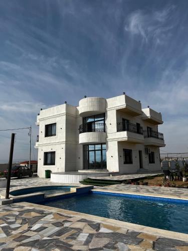 a building with a swimming pool in front of it at Rest Sea Chaliet & Farm in Edh Dhrā‘