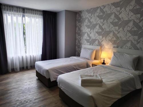 a hotel room with two beds and a window at SRITEL BOUTIQUE HOTEL in Shah Alam