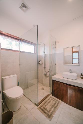 a bathroom with a toilet and a glass shower at Villa Ramira in General Luna