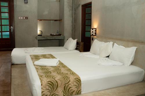 two beds in a hotel room with white sheets at Sayon River Cottage in Wellawaya