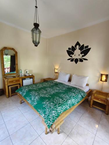 a bedroom with a large bed with a green comforter at Hotel Chonos in Lovina