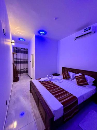 a bedroom with a large bed with purple lighting at Air Port Ama Villa - Transit Getaway in Katunayaka
