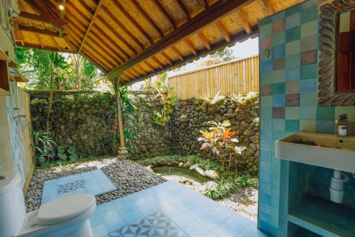a bathroom with a toilet and a stone wall at Unik Cottage in Sidemen