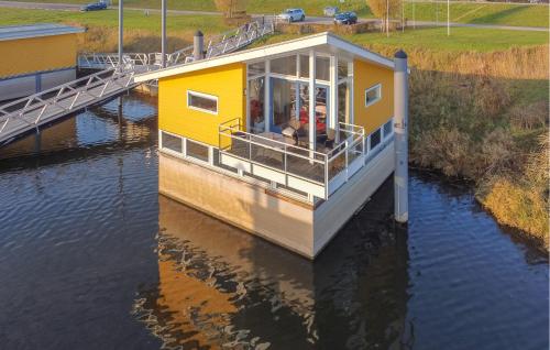 a yellow house on a boat in the water at Maasvilla - Amfibie - 31 in Ohé en Laak