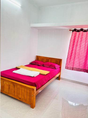 a bedroom with a bed with red sheets and a pink curtain at AAG Pride serviced apartments in Pollāchi
