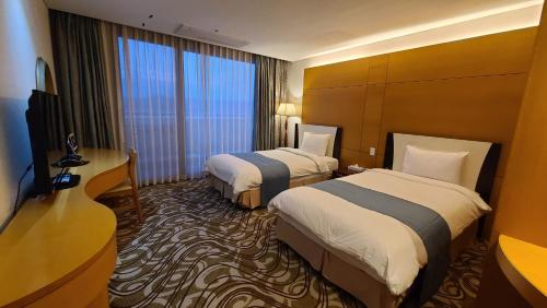 a hotel room with two beds and a television at Sun Valley Hotel in Yeoju