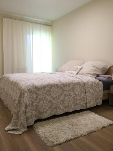 um quarto com uma cama com um cobertor branco e uma janela em Apartment - zentrumsnah, eigener Parkplatz und großer Balkon ins Grüne em Baden-Baden