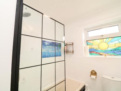 a bathroom with a glass shower stall and a window at 5 Overstone Drive in Wisbech