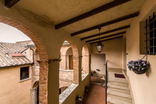 an alleyway in a building with arches and a flower pot at Bellarmino Boutique Apartments, Montepulciano in Montepulciano