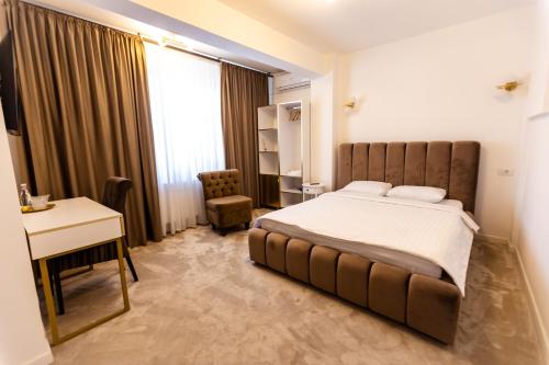 a hotel room with a bed and a desk and a window at Jolie Boutique Hotel in Craiova