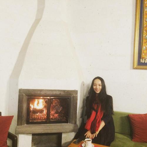 a woman sitting on a couch next to a fireplace at Ürgüp Inn Cave Hotel in Urgup