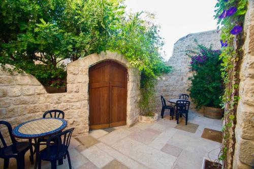 a patio with tables and chairs and a wooden door at Artist Quarter Guesthouse B&B in Safed