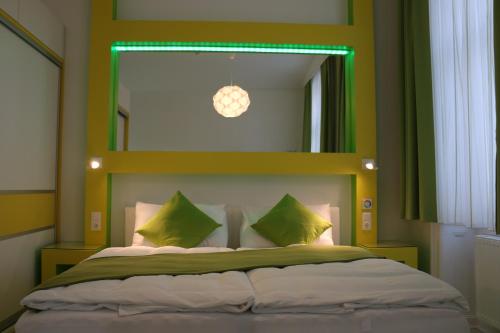 Schlafzimmer mit einem großen Bett mit einem grünen Kopfteil in der Unterkunft CH-Hotel Luka in Wien