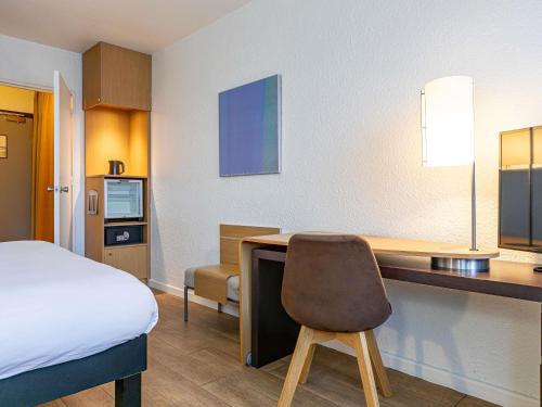 a room with a bed and a desk with a chair at Mercure Paris Le Bourget Aeroport in Le Blanc-Mesnil
