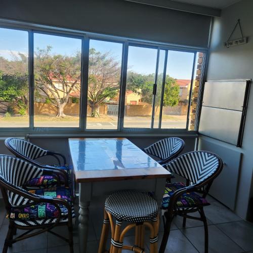 a table and chairs in a room with windows at Dolfyn201 La Mer in Hartenbos
