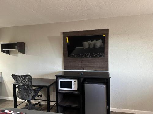 a room with a desk with a microwave and a chair at Rodeway Inn Jonesboro - Atlanta South in Jonesboro