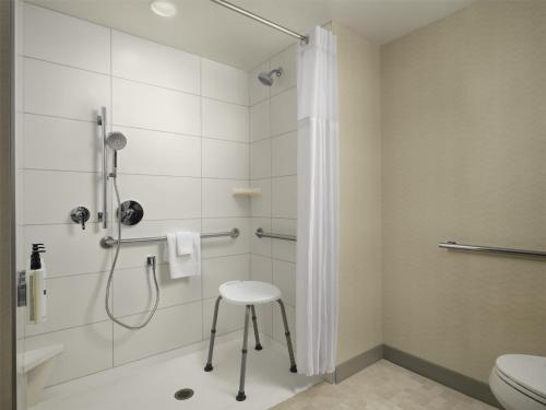 a bathroom with a shower with a stool in it at Hilton Garden Inn Merced in Merced