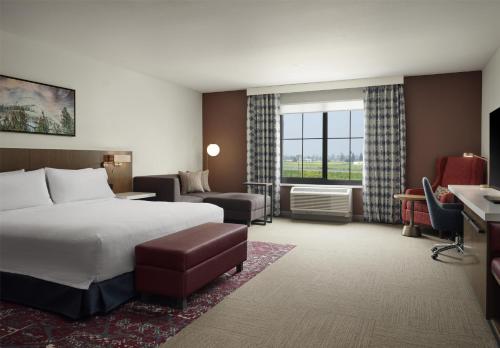 a hotel room with a bed and a desk and a room at Hilton Garden Inn Merced in Merced