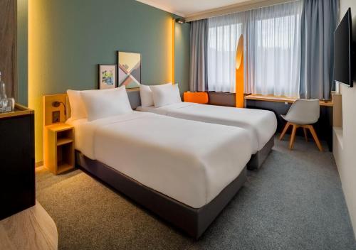 a hotel room with two beds and a chair at Spark by Hilton Wuppertal City Centre in Wuppertal