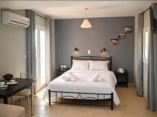 a bedroom with a large white bed with a desk at Rodanthy Studios IV in Katelios