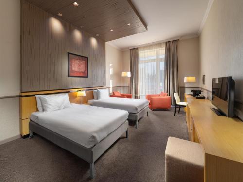 a hotel room with two beds and a television at Mamaison Hotel Andrassy Budapest in Budapest