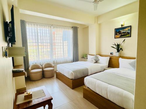 a hotel room with two beds and a window at Namaste Guest House in Pokhara