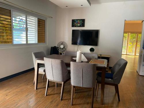 a dining room with a table and chairs and a television at CasaOlivia in Puerto Galera
