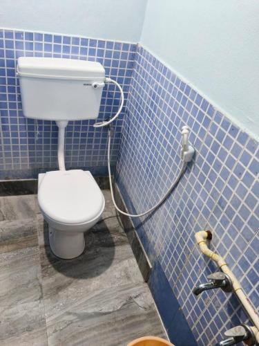 a bathroom with a toilet in a blue tiled wall at Sumathinandanakuteer in Pithāpuram