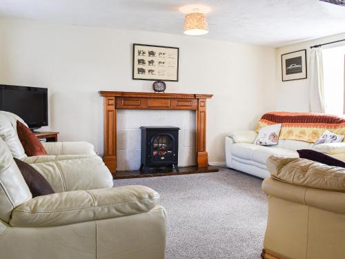 a living room with a fireplace and two couches at Meadow Cottage in Leek
