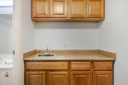 a kitchen with a sink and wooden cabinets at Rodeway Inn Auburn Hills - Detroit in Auburn Hills