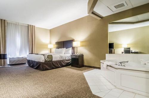 a hotel room with a bed and a tub and a sink at Quality Suites Graham - Burlington South in Graham