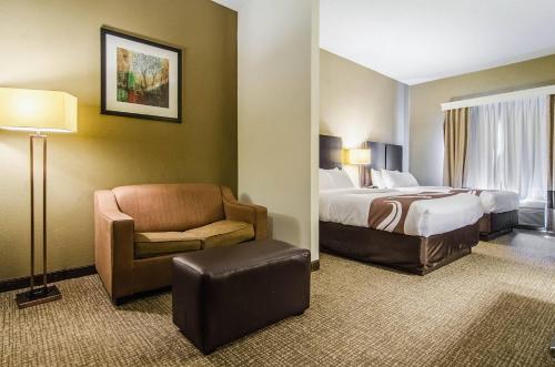 a hotel room with a bed and a chair at Quality Suites Graham - Burlington South in Graham