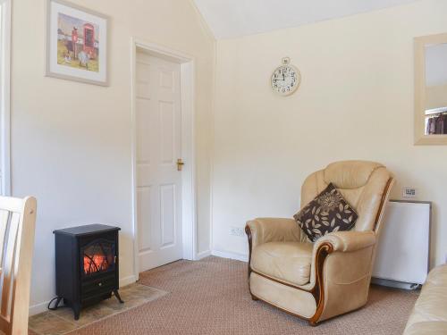a living room with a chair and a stove at Stable Cottage in Leek