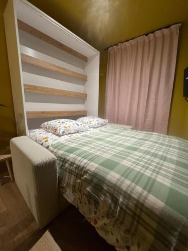 a bedroom with a bed with a green and white blanket at Studio confortable à proximité des thermes in Salies-de-Béarn