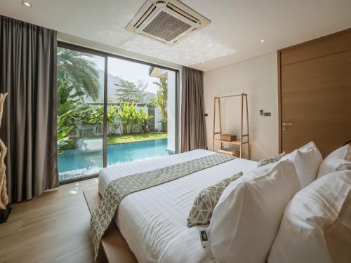 a bedroom with a large bed and a large window at Calypso Villa Phuket - Naiyang Beach in Nai Yang Beach
