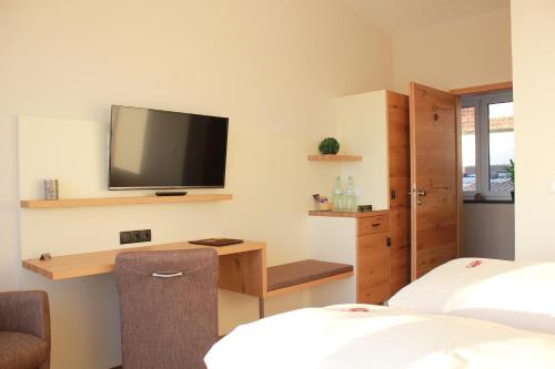 a room with two beds and a tv on the wall at Gästehaus Rebenhof in Neustadt an der Weinstraße