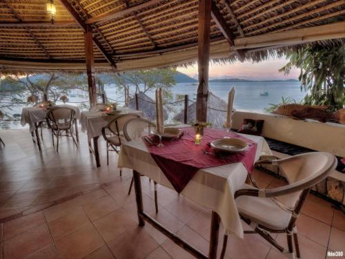 een restaurant met tafels en stoelen en uitzicht op de oceaan bij Auberge Le Maki Lodge in Ampangorinana