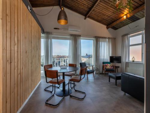 a living room with a table and chairs and windows at Lovely, modern, 4-person apartment in the heart of Koudekerke in Koudekerke