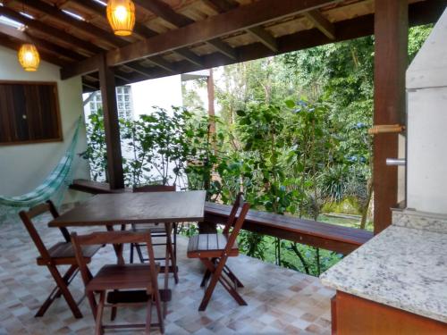 a porch with a table and chairs and a view of the forest at Casa e Chalé na Praia do Julião in Ilhabela