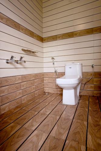 a bathroom with a toilet and a wooden floor at Koodaram Camping Munnar in Munnar