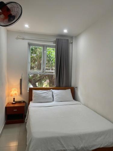 a bedroom with a white bed and a window at Motel Minh Thảo in Danang