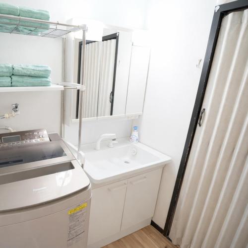 a white bathroom with a sink and a mirror at マンションルミエールＩ301 rumiereＩ301 in Gifu