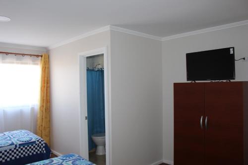 a bedroom with a bed and a flat screen tv on a wall at Alto El Quisco in El Quisco