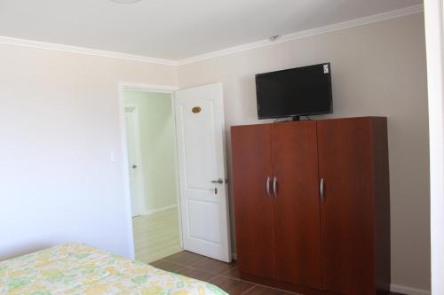 a bedroom with a tv on top of a wooden cabinet at Alto El Quisco in El Quisco
