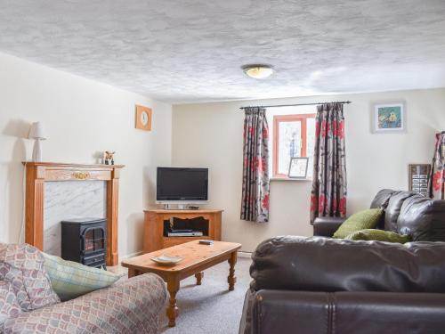 a living room with a couch and a tv at Swallow Cottage in Leek