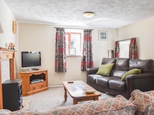 a living room with a couch and a tv at Swallow Cottage in Leek