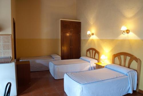 una habitación de hotel con 3 camas en una habitación en Aparthotel Las Palomas en La Puebla de los Infantes